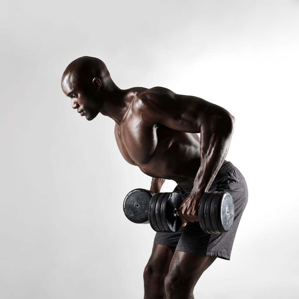 Bodybuilder mid-set on dumbbell work.