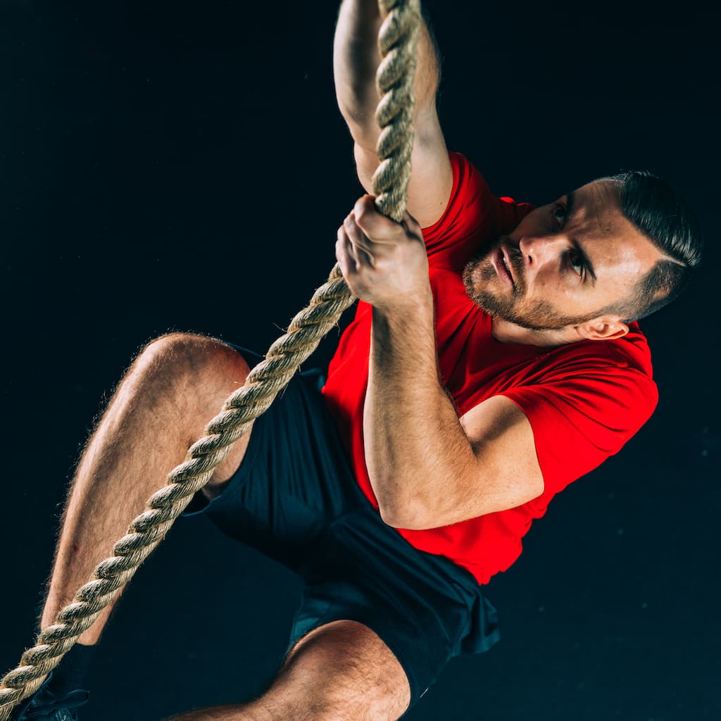 Athlete climbing rope in a cross-training session.